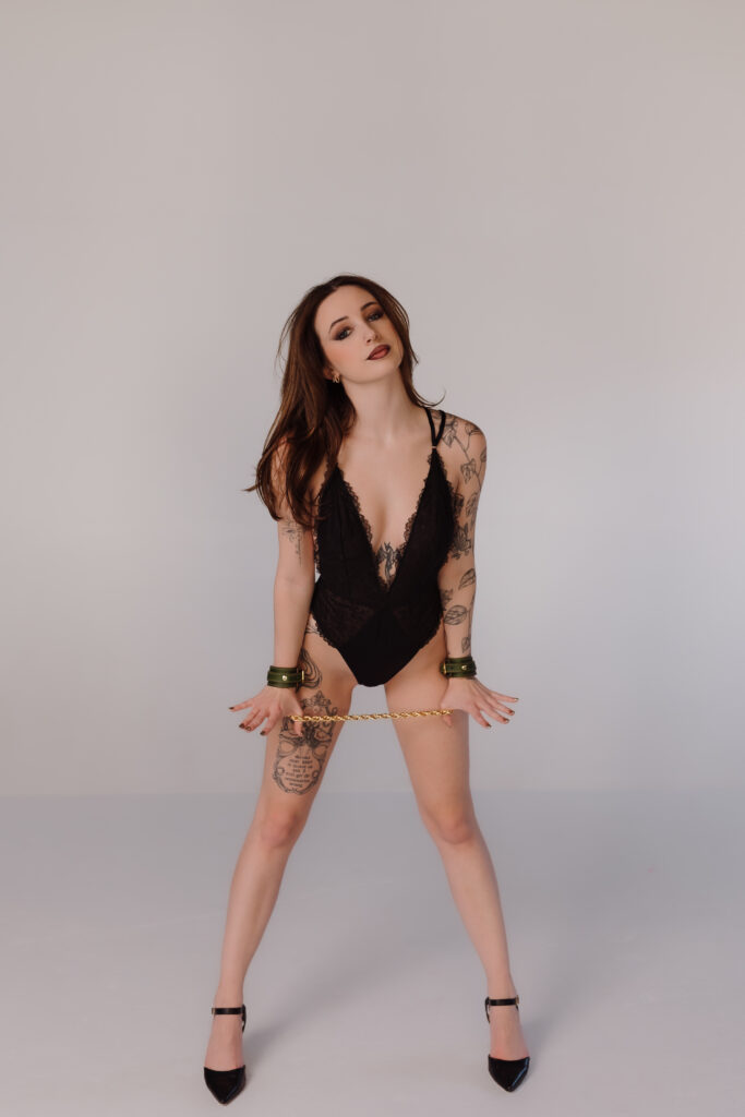 Boudoir photo by Oklahoma City photographer, Crystal Shaw, featuring green leather cuffs with gold connecting chain from Lovey Subby.