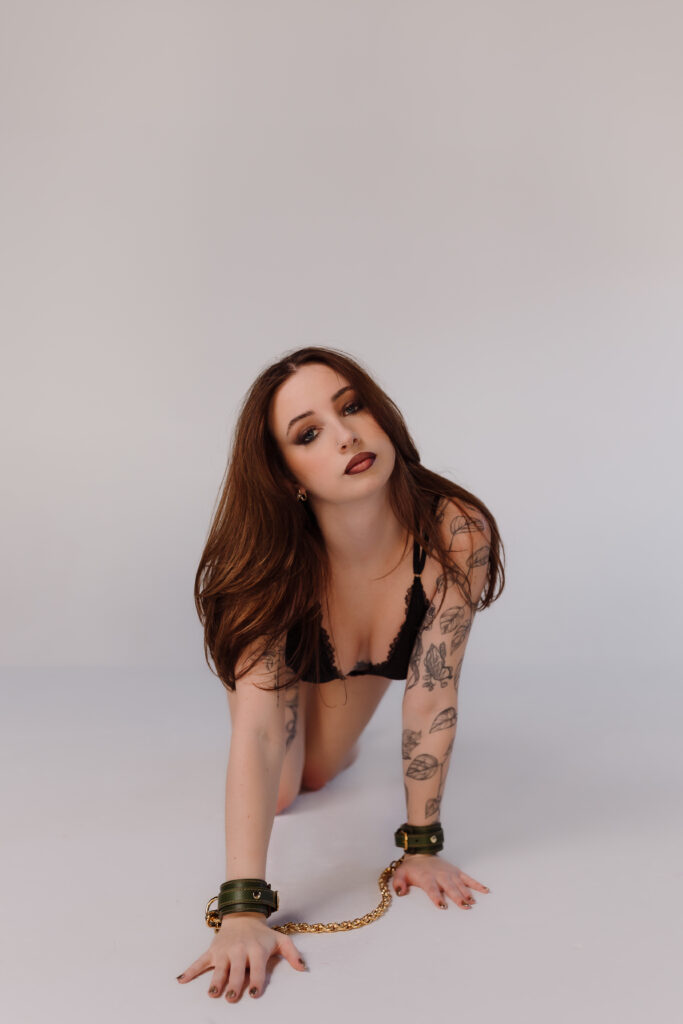Boudoir photo by Oklahoma City photographer, Crystal Shaw, featuring green leather cuffs with gold connecting chain from Lovey Subby.