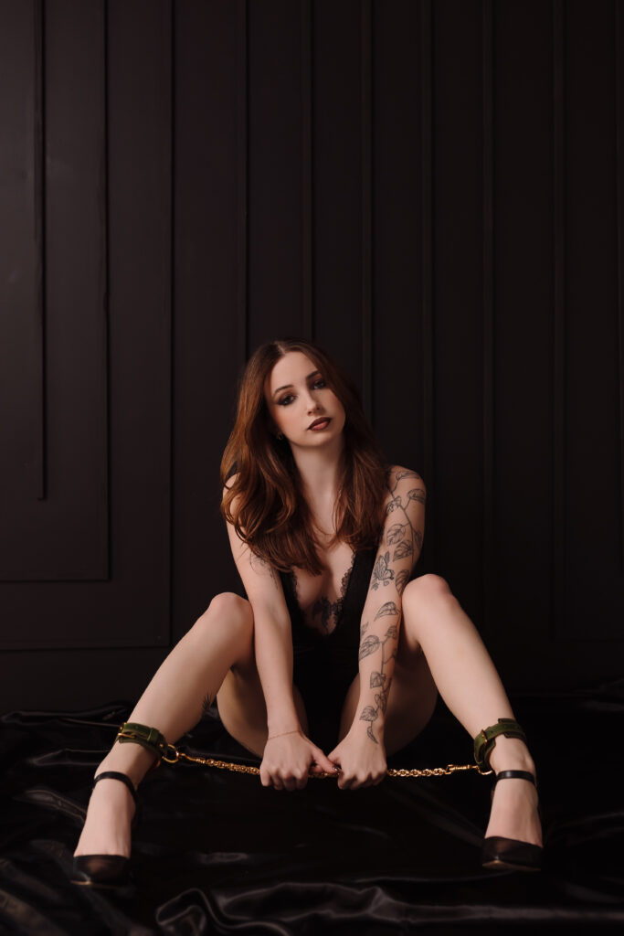 Boudoir photo by Oklahoma City photographer, Crystal Shaw, featuring green leather cuffs with gold connecting chain from Lovey Subby.